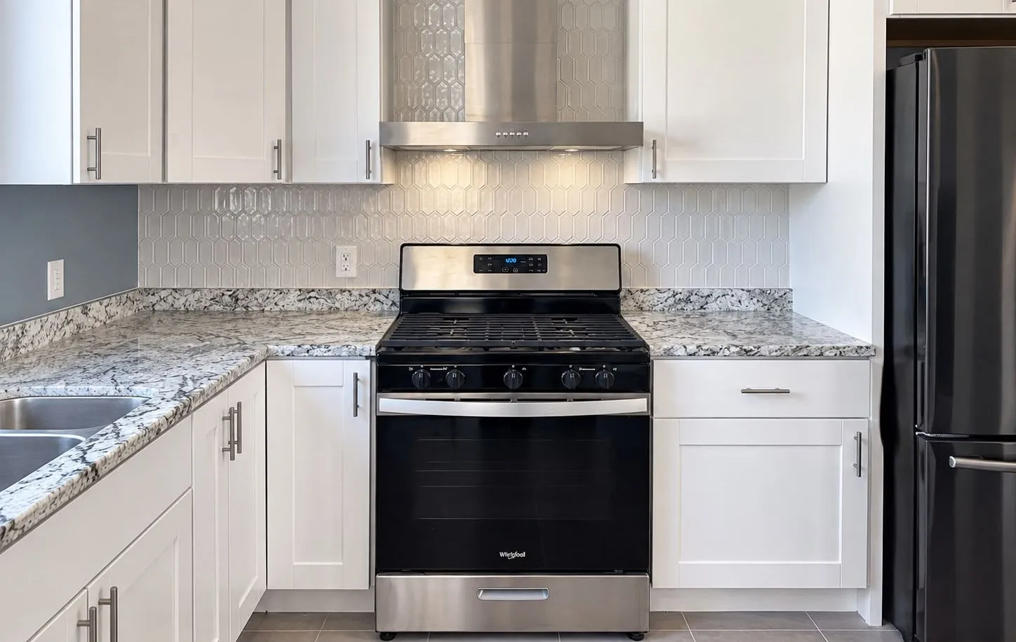Remodeled kitchen with a stainless steel range hood and hexagon tile backsplash