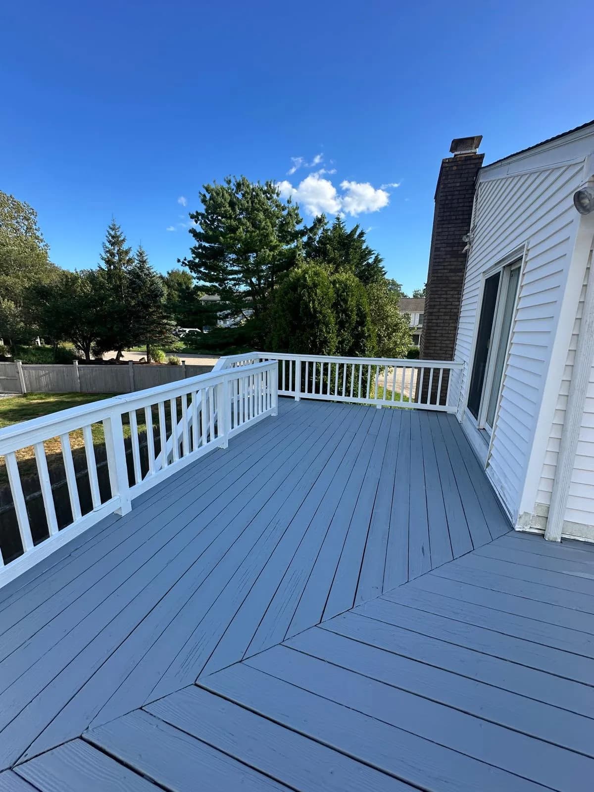 Painted gray deck with white railings overlooking the yard