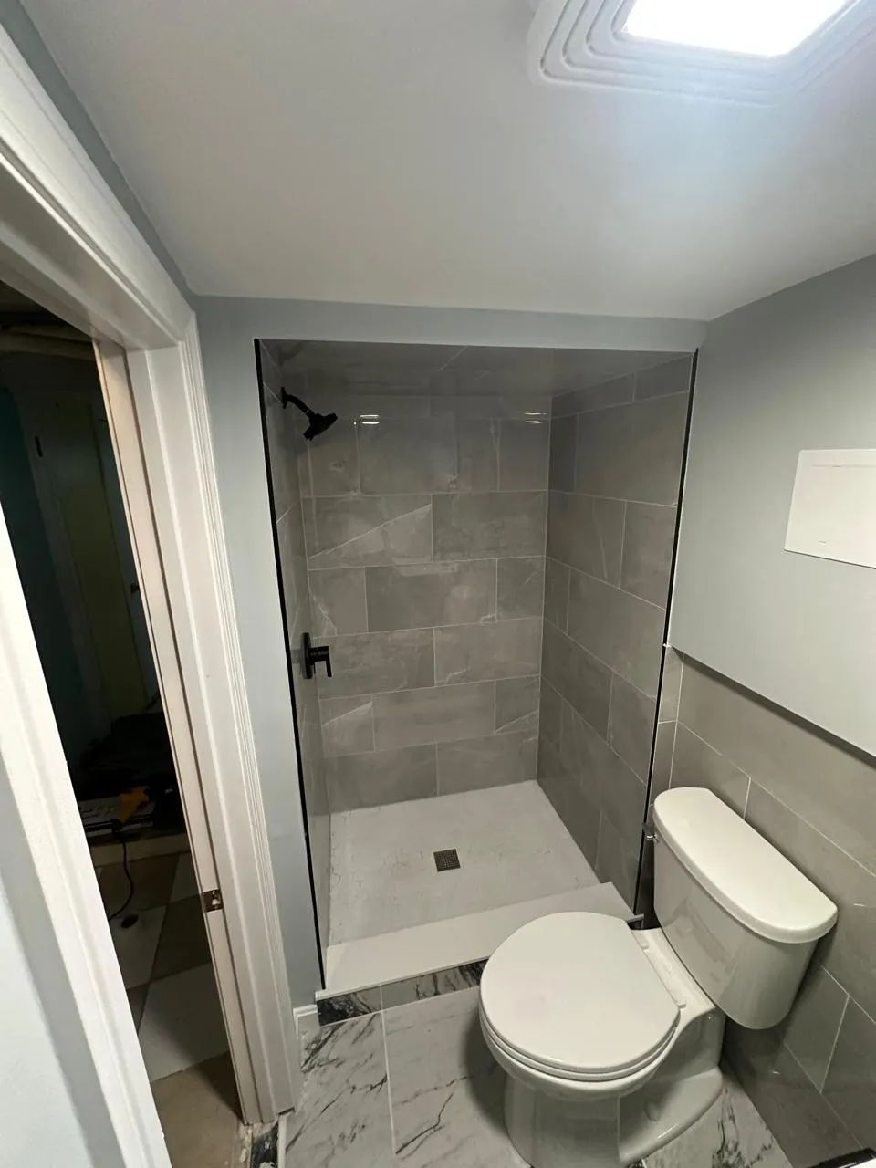 Tiled shower with frameless glass panel and marble-look flooring