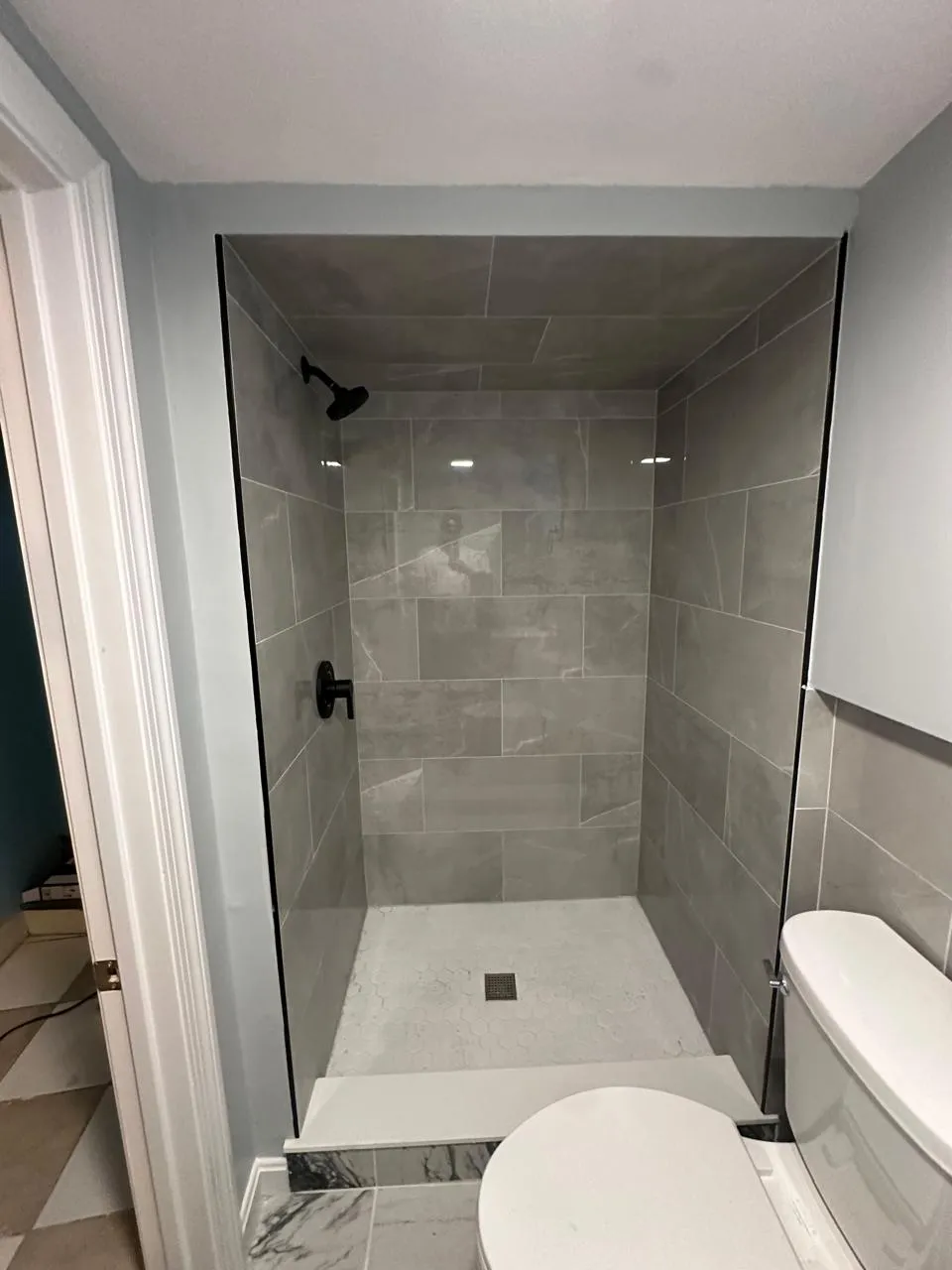 Tiled shower stall with glass panel and marble tile floor