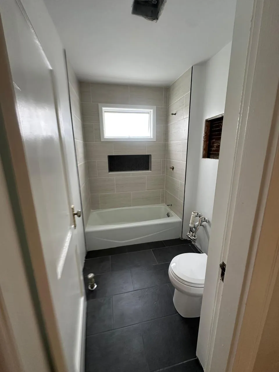Finished bathroom with tiled tub surround and slate floor