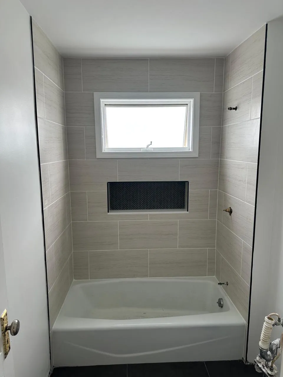 Tub surround in large-format tile with a dark accent niche