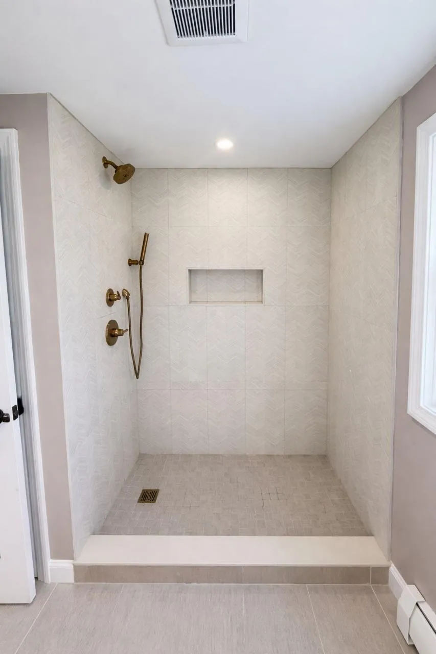 Curbless walk-in shower with herringbone tile and a recessed niche