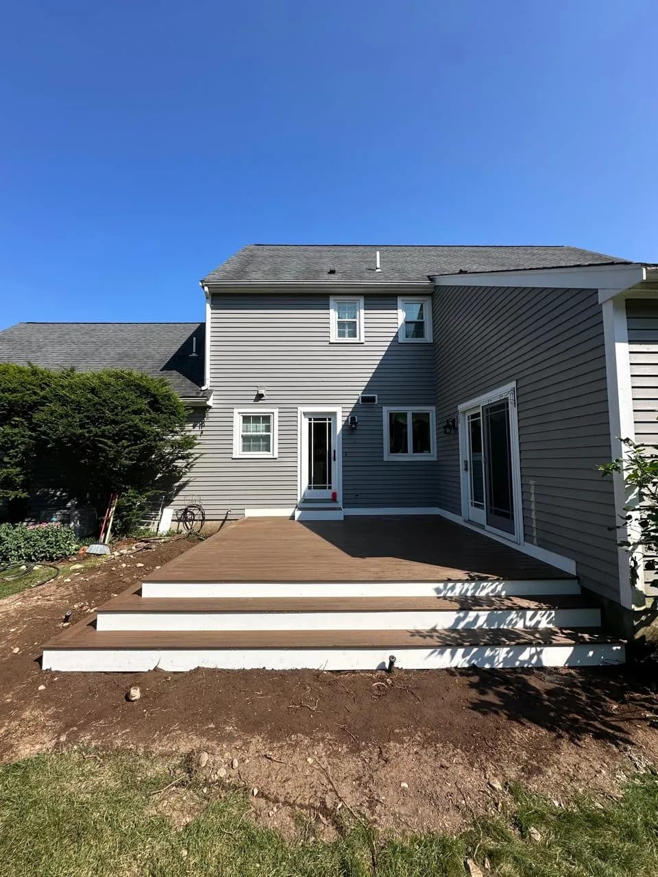 Composite deck spanning the back of a gray-sided home