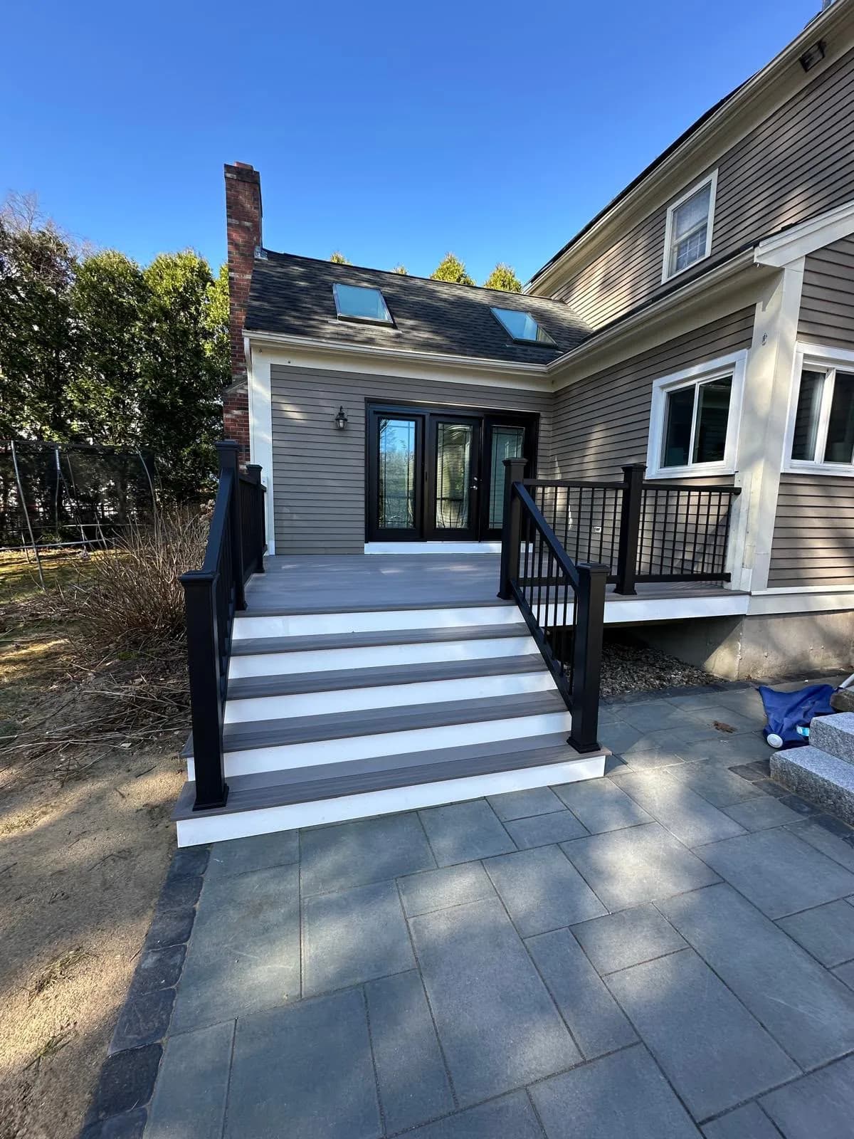 Covered composite deck with black railings leading to French doors