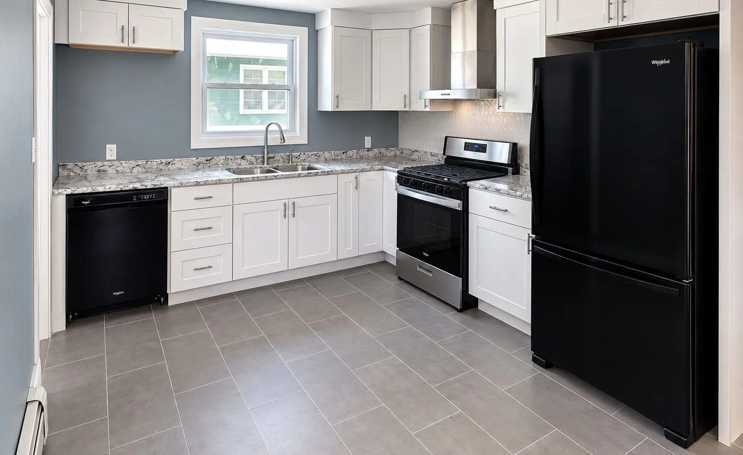 Remodeled kitchen with white shaker cabinets, granite counters, and black appliances